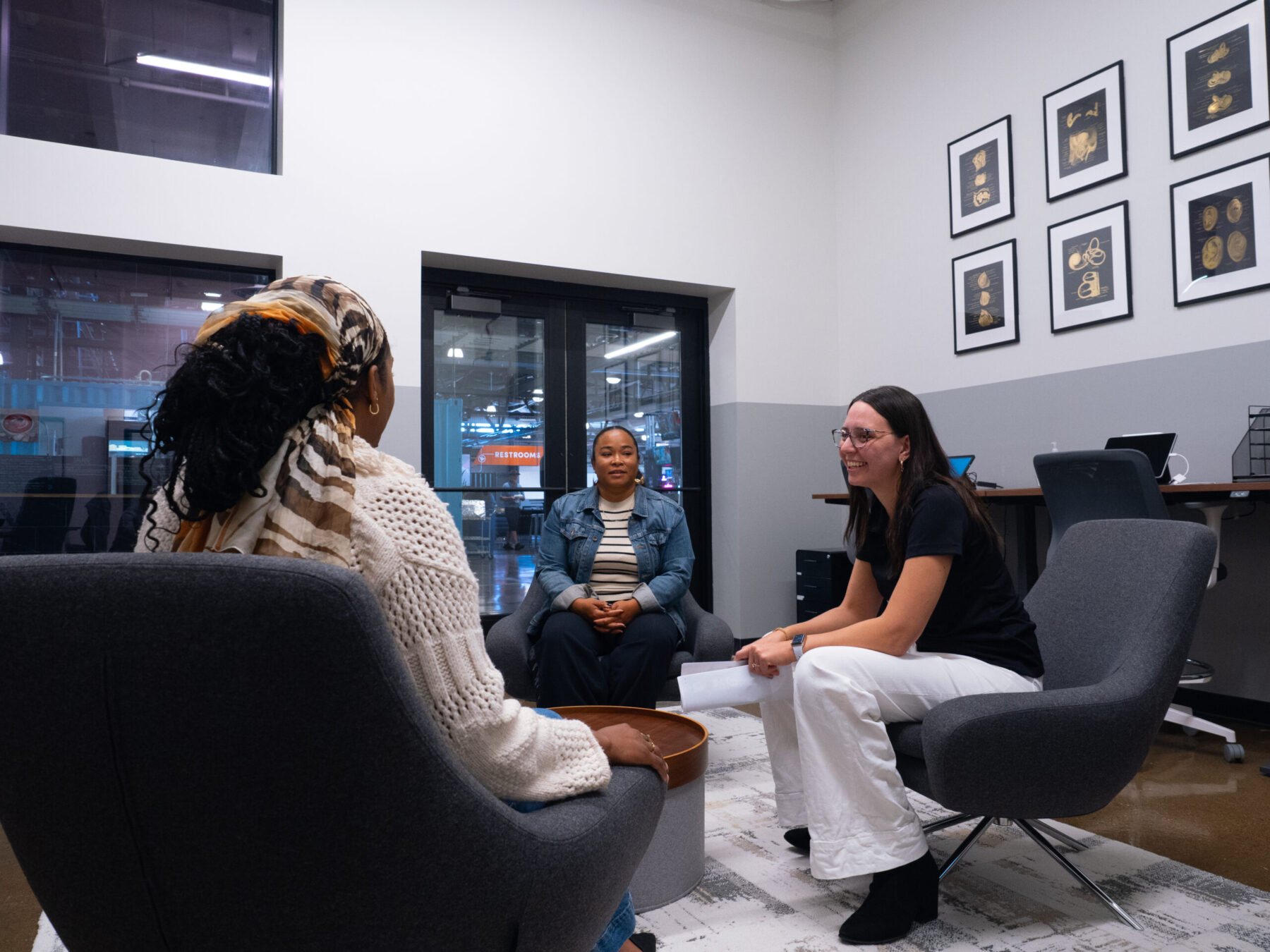 Three people seated in conversation in the APARC reception area.